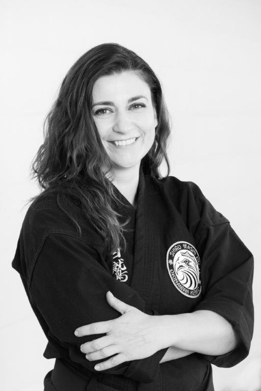 Instructor Magdalena Zubek Ciecwierz smiling in a black karate gi, representing Polander Academy of Martial Arts in Bethesda.