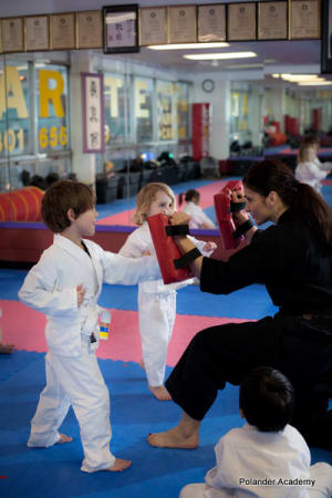 Kids practicing karate with instructor at Polander Academy in Bethesda, demonstrating martial arts techniques and teamwork.