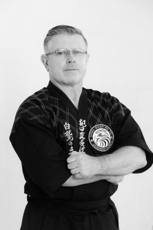 Head instructor Peter Ciecwierz Polander in martial arts uniform, arms crossed, promoting Polander Academy of Martial Arts in Bethesda.