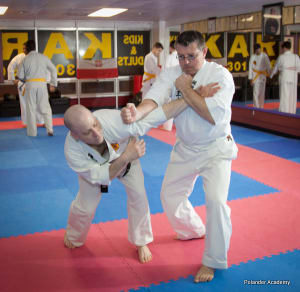 Two martial arts practitioners demonstrating a self-defense technique during an adult karate class at Polander Academy of Martial Arts in Bethesda, Maryland.