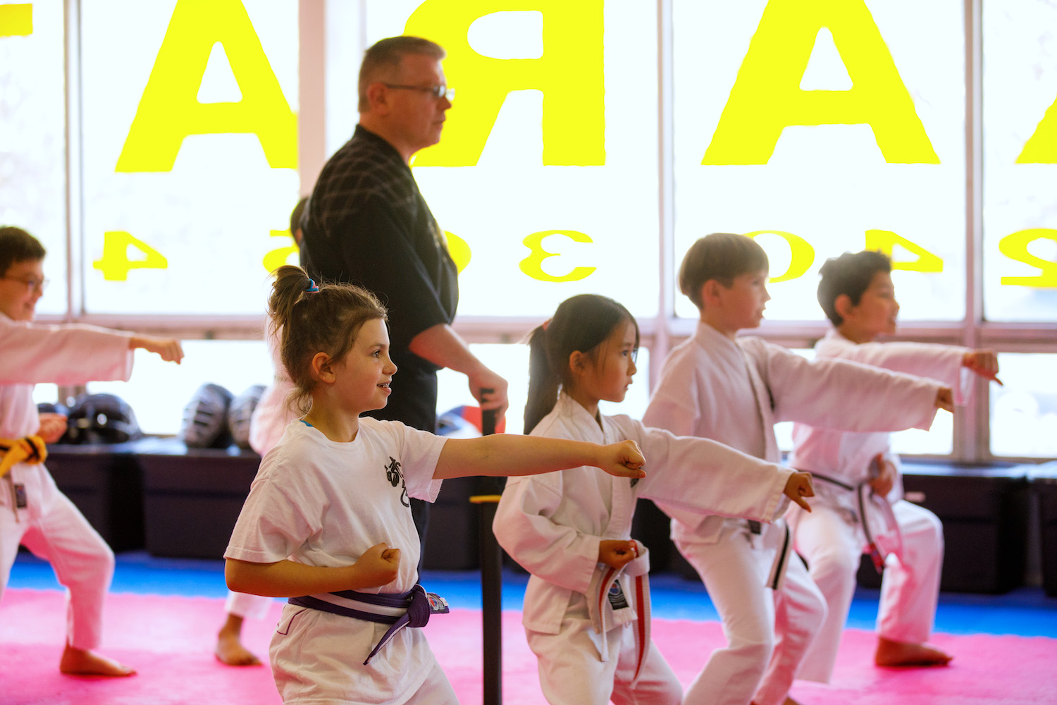 Children practicing karate in a dojo, led by an instructor, emphasizing focus and discipline in Bethesda.