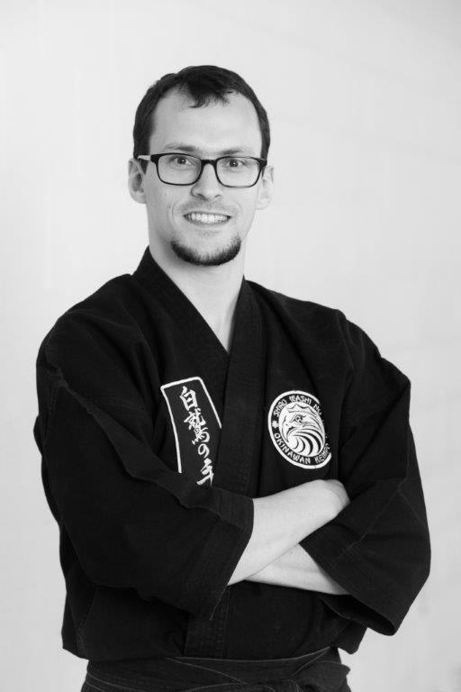 Instructor in black karate gi with arms crossed, showcasing martial arts expertise at Polander Academy of Martial Arts in Bethesda.